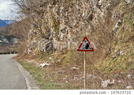 A sign warning of rock falls along a highway in the mountains A sign warning of rock falls along a highway in the mountains 107633728