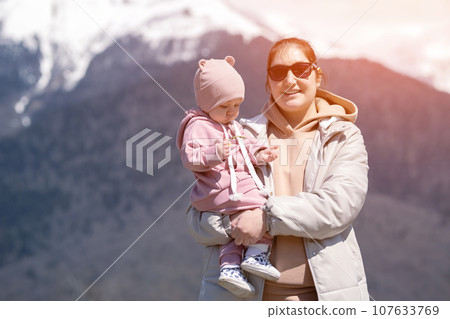 Mother in sunglasses holding daughter enjoys mountain visit Mother in sunglasses holding daughter enjoys mountain visit 107633769