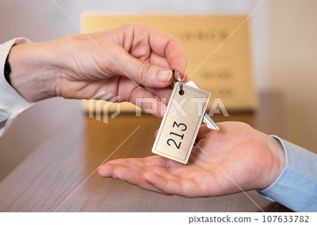 Receptionist gives key to customer at check-in desk Receptionist gives key to customer at check-in desk 107633782