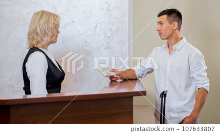 Young man handing over passport to find reserved hotel room 107633807