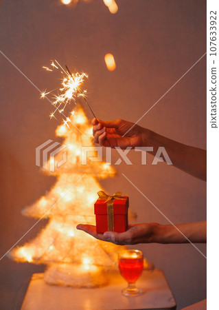 sparkler in woman's hand, gift birthday or Christmas party. shining spark lights 107633922