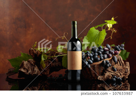 Bottle of red wine with blue grapes and vine branches. Bottle of red wine with blue grapes and vine branches. 107633987