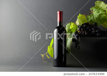 Bottle of red wine with blue grapes and vine branches. Bottle of red wine with blue grapes and vine branches. 107633990