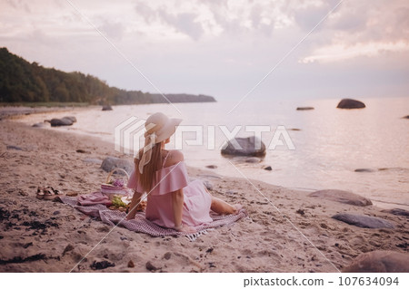Young woman in straw hat sit on plaid have picnic on sea sunrise sand beach  107634094