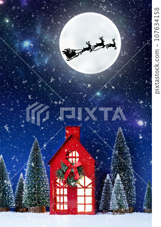 Still life of red Christmas toy house and Santa Clause sleigh over full moon. Creative Christmas composition with Santa Clause. Christmas background. 107634158