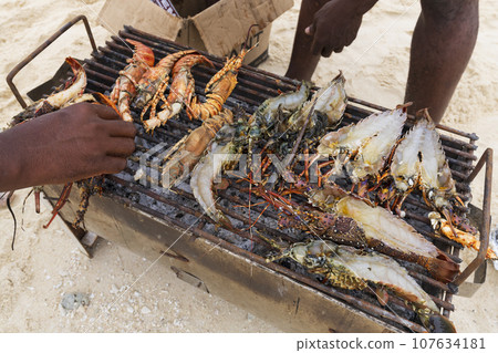 Lobsters and prawns cooked on small grill at the beach Lobsters and prawns cooked on small grill at the beach 107634181