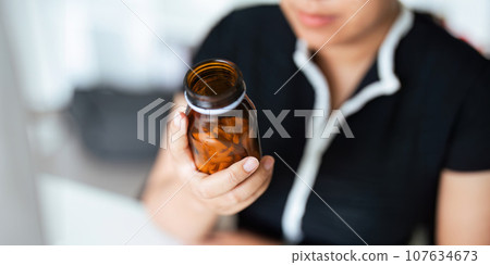 Woman hold bottle of drug tablet painkiller or vitamin supplement reading label ready to organizing medicine at home. medication healthcare concept Woman hold bottle of drug tablet painkiller or vitamin supplement reading label ready to organizing medicine at home. medication healthcare concept 107634673