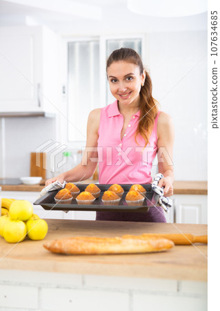 Portrait of cheerful housewife with cupcakes Portrait of cheerful housewife with cupcakes 107634685