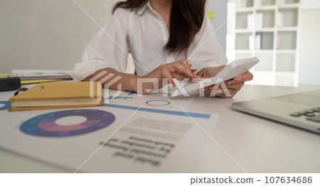 Businesswoman accountant using calculator and laptop for financial data saving in office room, Business financial, tax, accounting concept Businesswoman accountant using calculator and laptop for financial data saving in office room, Business financial, tax, accounting concept 107634686