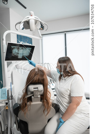 The dentist examines the results of a CT scan of the patient's mouth for an accurate diagnosis. Patients can expect the highest standard of dental care in a modern medical center. The dentist examines the results of a CT scan of the patient's mouth for an accurate diagnosis. Patients can expect the highest standard of dental care in a modern medical center. 107634708