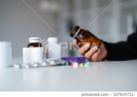 Woman hold bottle of drug tablet painkiller or vitamin supplement reading label ready to organizing medicine at home. medication healthcare concept Woman hold bottle of drug tablet painkiller or vitamin supplement reading label ready to organizing medicine at home. medication healthcare concept 107634722