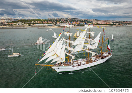 Aerial drone view of tall ships with sails sailing in Tagus river towards the Atlantic ocean in Lisbon, Portugal Aerial drone view of tall ships with sails sailing in Tagus river towards the Atlantic ocean in Lisbon, Portugal 107634775
