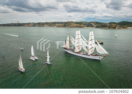 Aerial drone view of tall ships with sails sailing in Tagus river towards the Atlantic ocean in Lisbon, Portugal 107634802