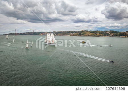 Aerial drone view of tall ships with sails sailing in Tagus river towards the Atlantic ocean in Lisbon, Portugal Aerial drone view of tall ships with sails sailing in Tagus river towards the Atlantic ocean in Lisbon, Portugal 107634806