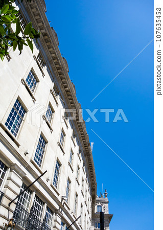 Curved historic stone buildings lined up on Regent Street under a bright blue clear sky, London cityscape Curved historic stone buildings lined up on Regent Street under a bright blue clear sky, London cityscape 107635458