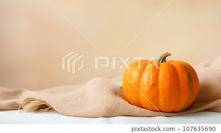 Autumn cozy still life with pumpkin on a tablecloth, neutral pastel background 107635690