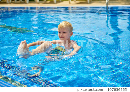 Young boy kid child eight years old splashing in swimming pool having fun leisure activity. Boy happy swimming in a pool. Activities on the pool, children swimming and playing in water, happiness and Young boy kid child eight years old splashing in swimming pool having fun leisure activity. Boy happy swimming in a pool. Activities on the pool, children swimming and playing in water, happiness and 107636365