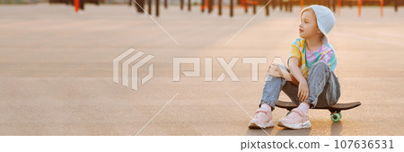 A child or girl skater sits on a skateboard. A child or girl skater sits on a skateboard. 107636531