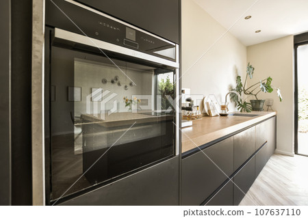 a modern kitchen with wood counter tops and stainless steel oven hoods on the wall behind it is an open door 107637110