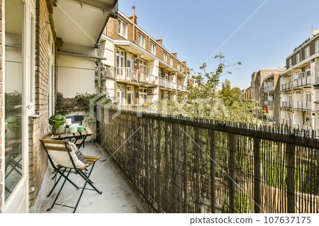 a balcony with chairs, tables and an umbrella on the side of the street in front of some apartment buildings a balcony with chairs, tables and an umbrella on the side of the street in front of some apartment buildings 107637175