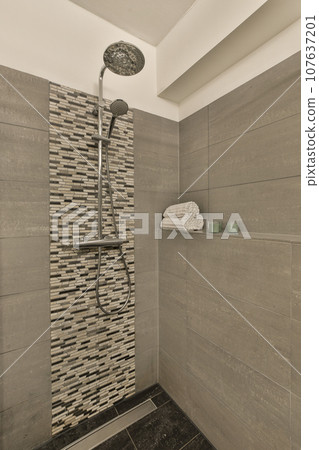 a bathroom with tiled walls and shower head mounted on the wall next to the toilet in the corner of the room 107637201