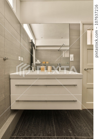 a modern bathroom with black tile flooring and white sink in the center of the image is an open door 107637216