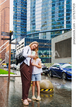 Mom and daughter walk between skyscrapers and shoot everything around. Mom and daughter walk between skyscrapers and shoot everything around. 107637459