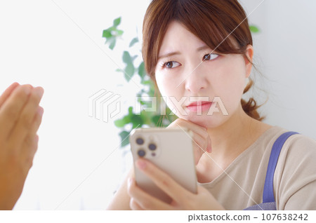 A woman makes a complicated expression when looking at a man's smartphone A woman makes a complicated expression when looking at a man's smartphone 107638242