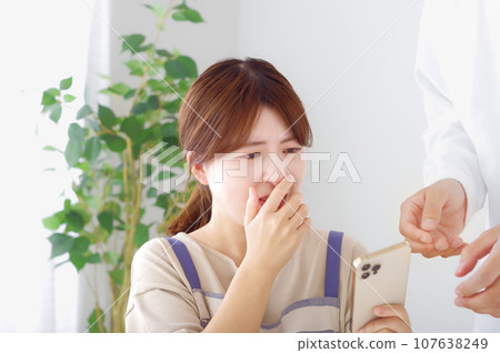 A woman makes a complicated expression when looking at a man's smartphone 107638249