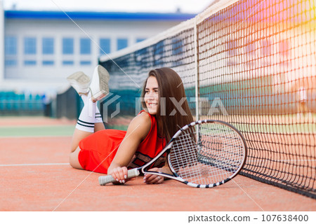 Beautiful female tennis player on tennis court. Red dress. Beautiful female tennis player on tennis court. Red dress. 107638400