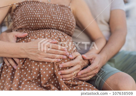 A happy, mature couple over 40, enjoying a leisurely walk in a park, their joy evident as they embrace the journey of pregnancy later in life A happy, mature couple over 40, enjoying a leisurely walk in a park, their joy evident as they embrace the journey of pregnancy later in life 107638509
