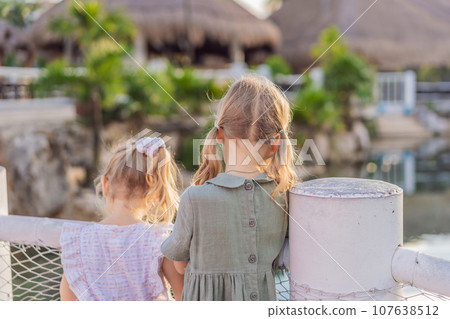 Two little girls take a delightful stroll along the yacht marina, their faces filled with wonder as they explore the world of boats and the sparkling waters Two little girls take a delightful stroll along the yacht marina, their faces filled with wonder as they explore the world of boats and the sparkling waters 107638512