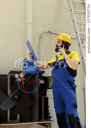 Adept repairman on the phone with client reporting found concerns about condenser during comissioned troubleshooting. Electrician going over hvac system warranty details with customer while on call Adept repairman on the phone with client reporting found concerns about condenser during comissioned troubleshooting. Electrician going over hvac system warranty details with customer while on call 107638754