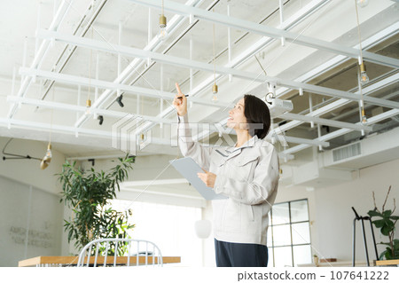 一名穿著工作服的婦女正在進行建築維護 一名穿著工作服的婦女正在進行建築維護 107641222