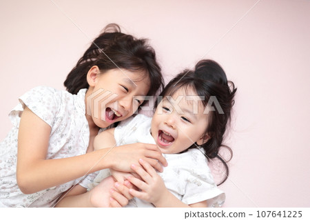 親密的姐妹躺在床上玩耍 親密的姐妹躺在床上玩耍 107641225