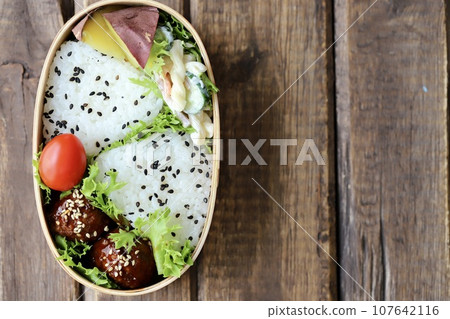 A bento lunch of sesame and salt rice balls in a bento box 107642116