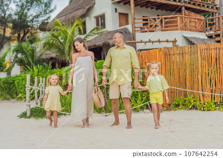 A joyful family, two girls, dad, and a pregnant mom, bask in tropical beach bliss, celebrating a radiant pregnancy amidst paradise A joyful family, two girls, dad, and a pregnant mom, bask in tropical beach bliss, celebrating a radiant pregnancy amidst paradise 107642254