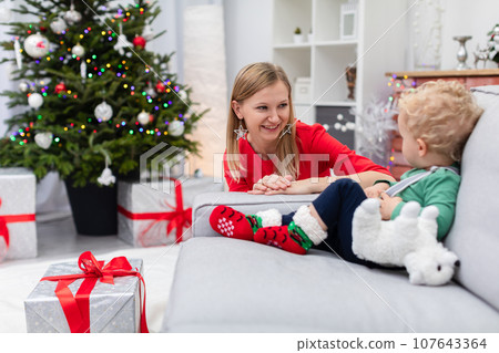 Son and his mother spending Christmas together against the backdrop of a decorated Christmas tree 107643364