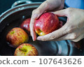 woman hand is cleaning red apple in bucket of water, closed up shot 107643626