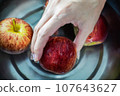 woman hand is cleaning red apple in bucket of water, closed up shot 107643627