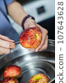 woman hand is cleaning red apple in bucket of water, closed up shot 107643628