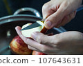 woman hand is cleaning red apple in bucket of water, closed up shot 107643631