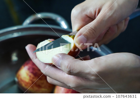 woman hand is cleaning red apple in bucket of water, closed up shot woman hand is cleaning red apple in bucket of water, closed up shot 107643631