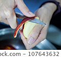 woman hand is cleaning red apple in bucket of water, closed up shot 107643632