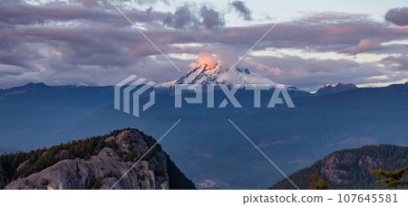 Mountain Peak Covered in clouds and snow. Dramatic Sunset Sky. Aerial Nature Background. Mountain Peak Covered in clouds and snow. Dramatic Sunset Sky. Aerial Nature Background. 107645581