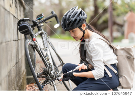 年輕女子用便攜式幫浦將空氣泵入公路自行車 107645947