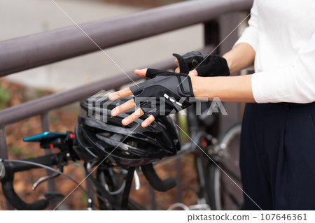Young woman wearing cycling gloves next to her road bike Young woman wearing cycling gloves next to her road bike 107646361