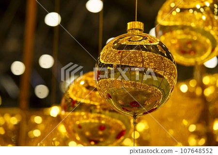Christmas decoration of a public space with large golden balls. Golden shiny, New Year's, holiday decor with festive glass Christmas tree balls of a restaurant, shopping center. Christmas decoration of a public space with large golden balls. Golden shiny, New Year's, holiday decor with festive glass Christmas tree balls of a restaurant, shopping center. 107648552