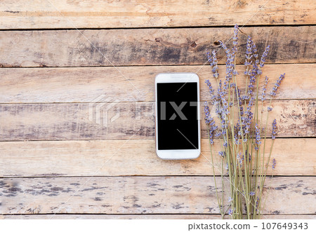 Smart phone and lavender flower on old wooden table background. Smart phone and lavender flower on old wooden table background. 107649343