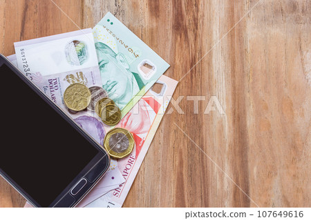 Smart phone and singapore dollar on wooden table 107649616